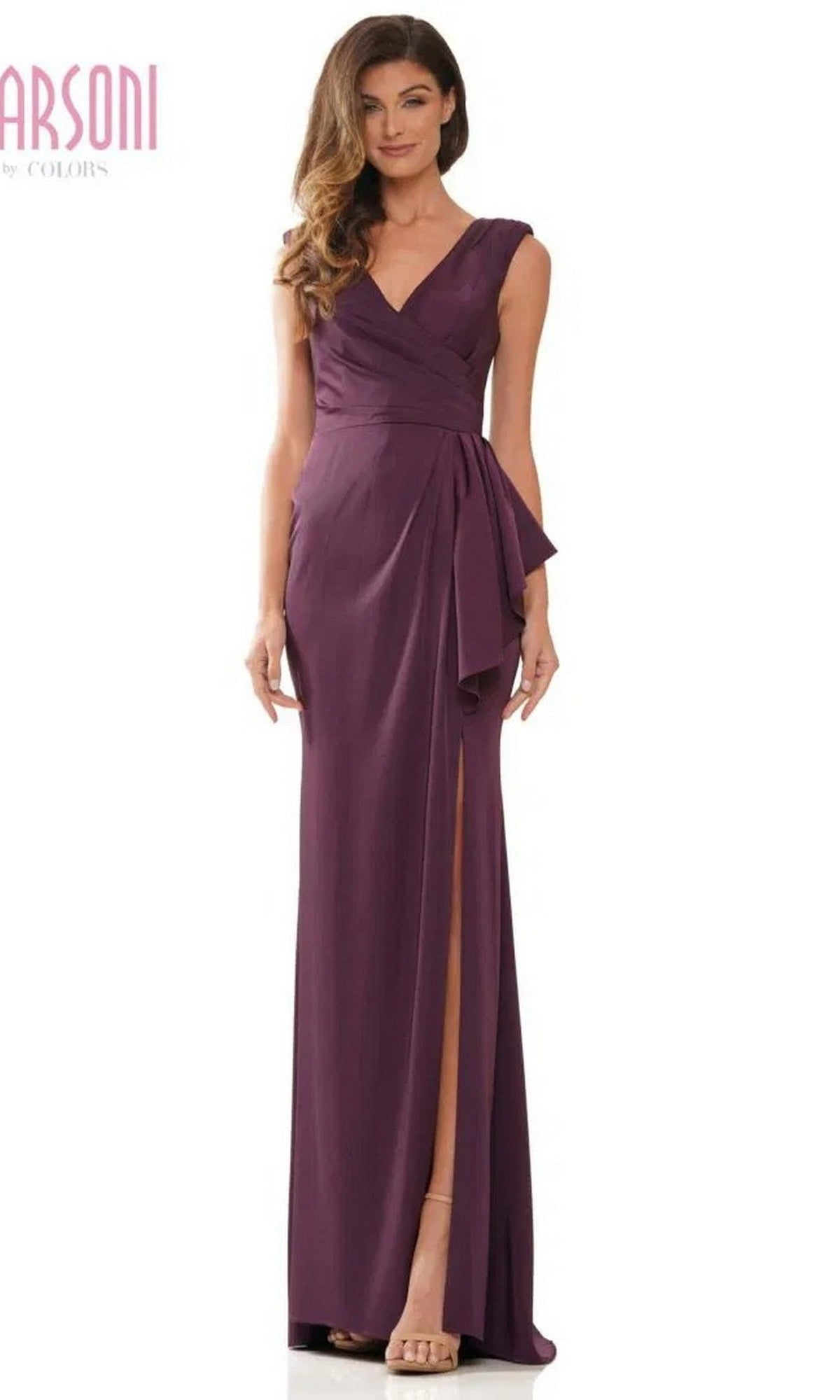 A woman models the Marsoni MV1227 long formal dress in eggplant, featuring a sleeveless wrap-style ruched bodice, V-neckline, side sash, left high slit, and floor-length sheath silhouette against a plain white backdrop.